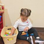 young girl playing with toys from basket