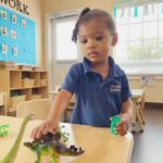 little girl playing with dinosaurs