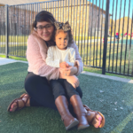 young girl being hugged by teacher outside