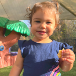 young girl with snack in hand outside