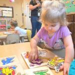 young girl playing with dinosaur puzzles