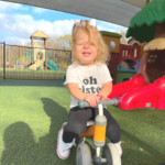 little girl laughing on bike outside