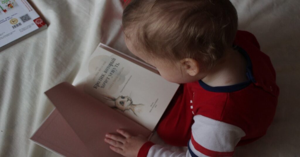 baby with book on bed