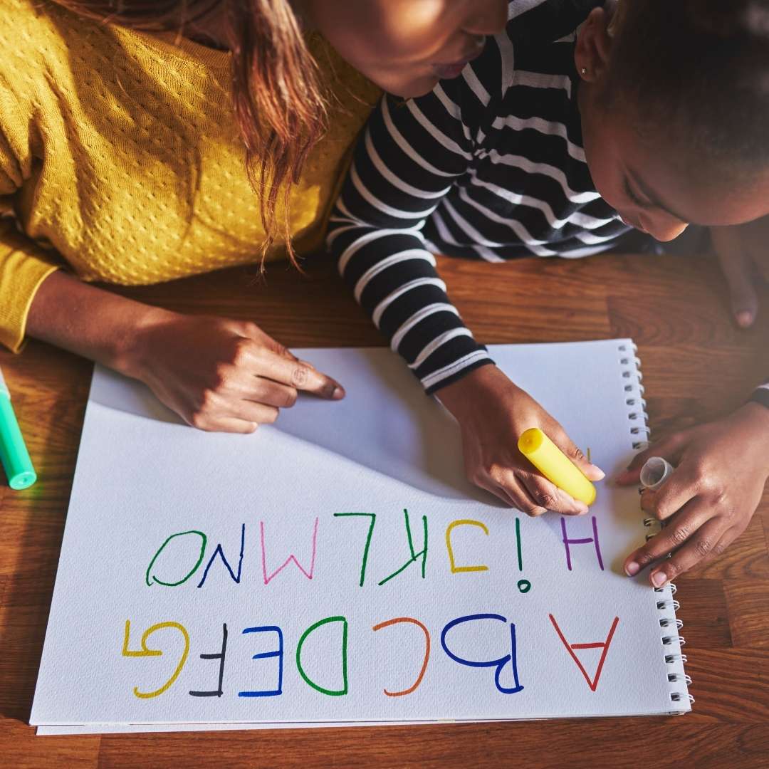 Teacher helping child write the ABC's