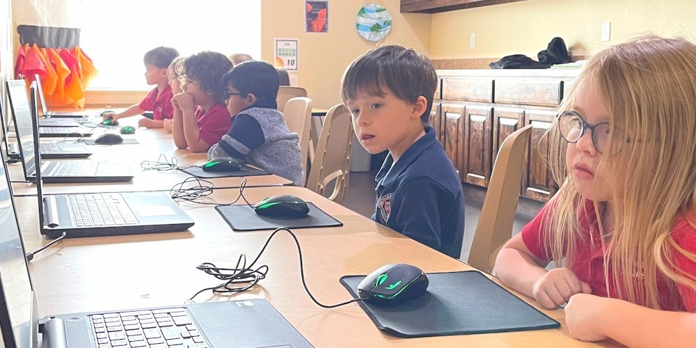 row of children at laptops