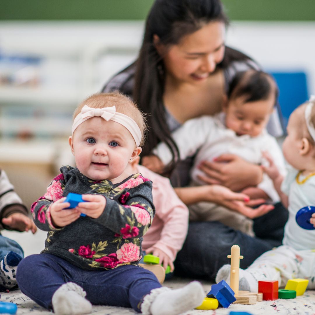 a little infant sitting on the floor at daycare
