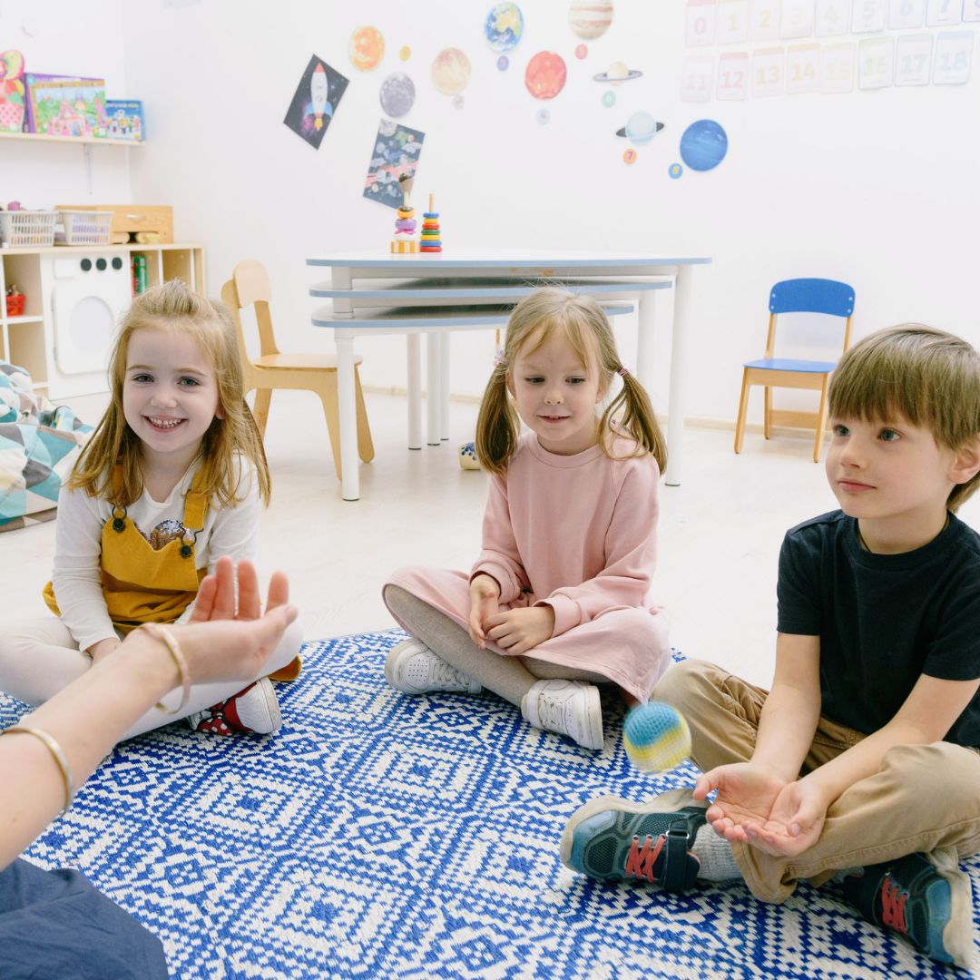 three kids sitting on a mat listening