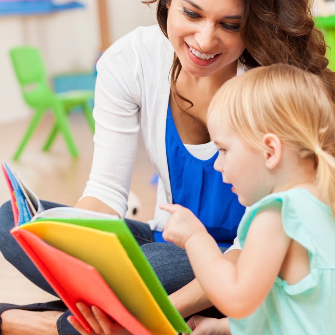 a teacher reading a little girl a book