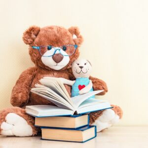stuffed toys _reading_ a stack of books