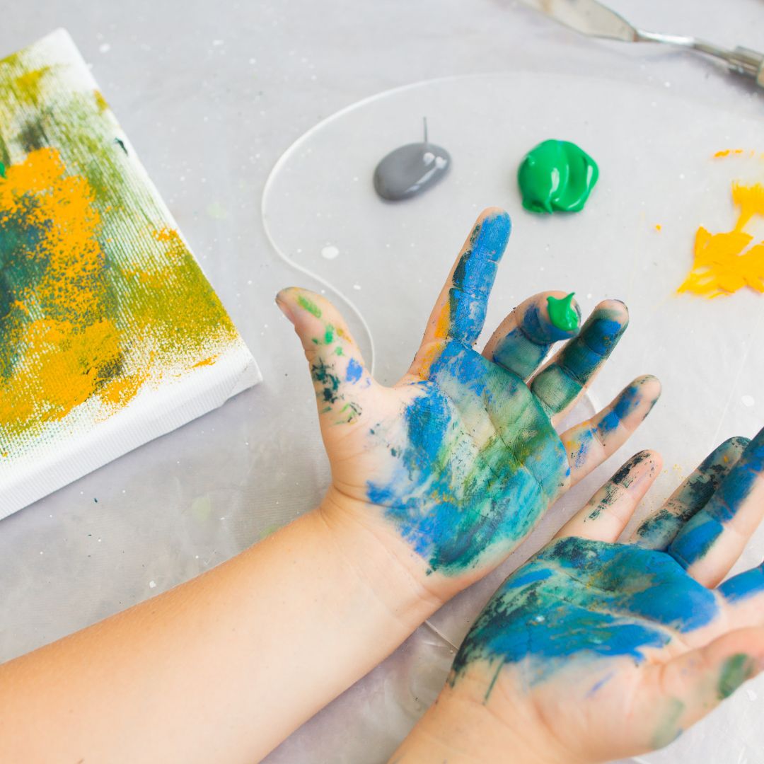 a little kids hands covered in paint