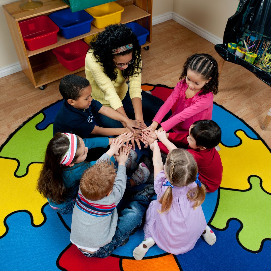 kids sitting on floor with hands in the middle