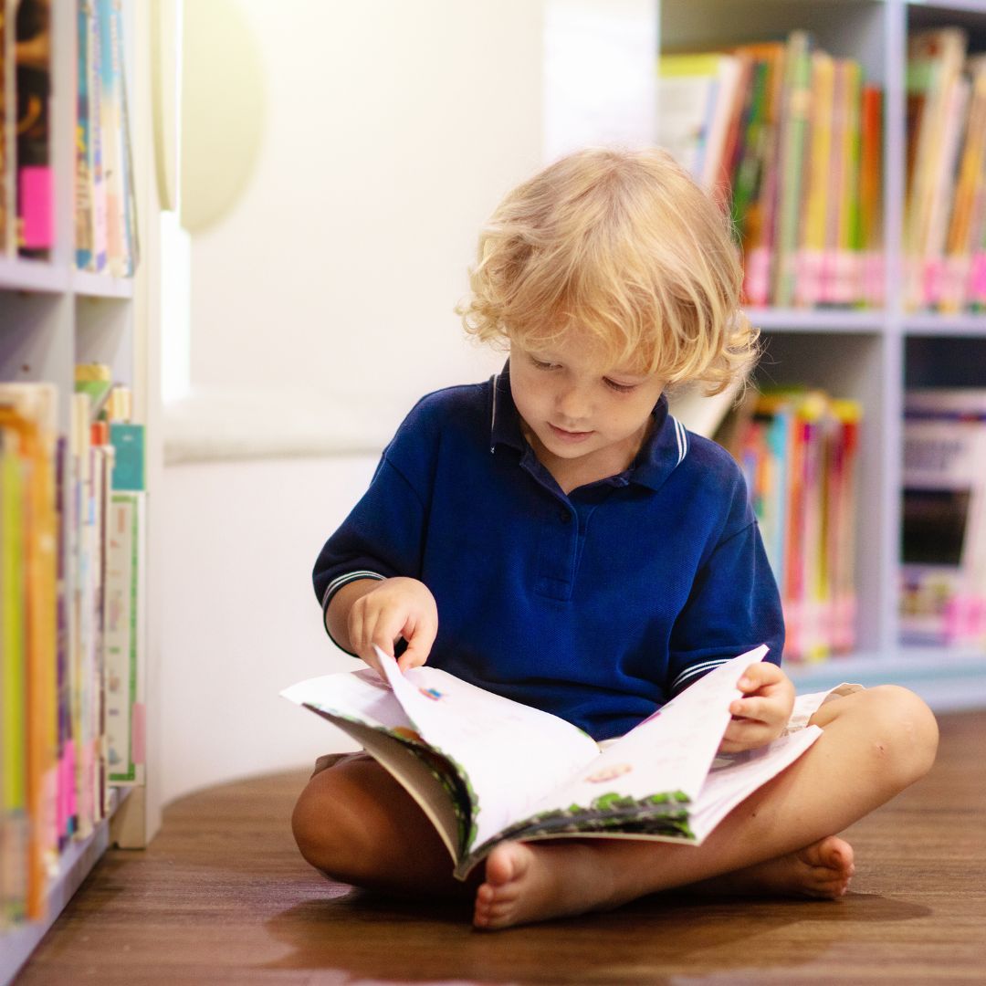 child sitting on floor reading picture book