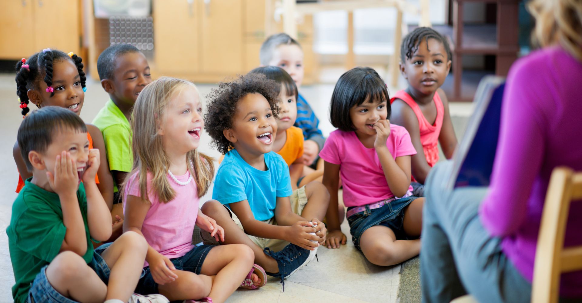children sitting on floor around instructor