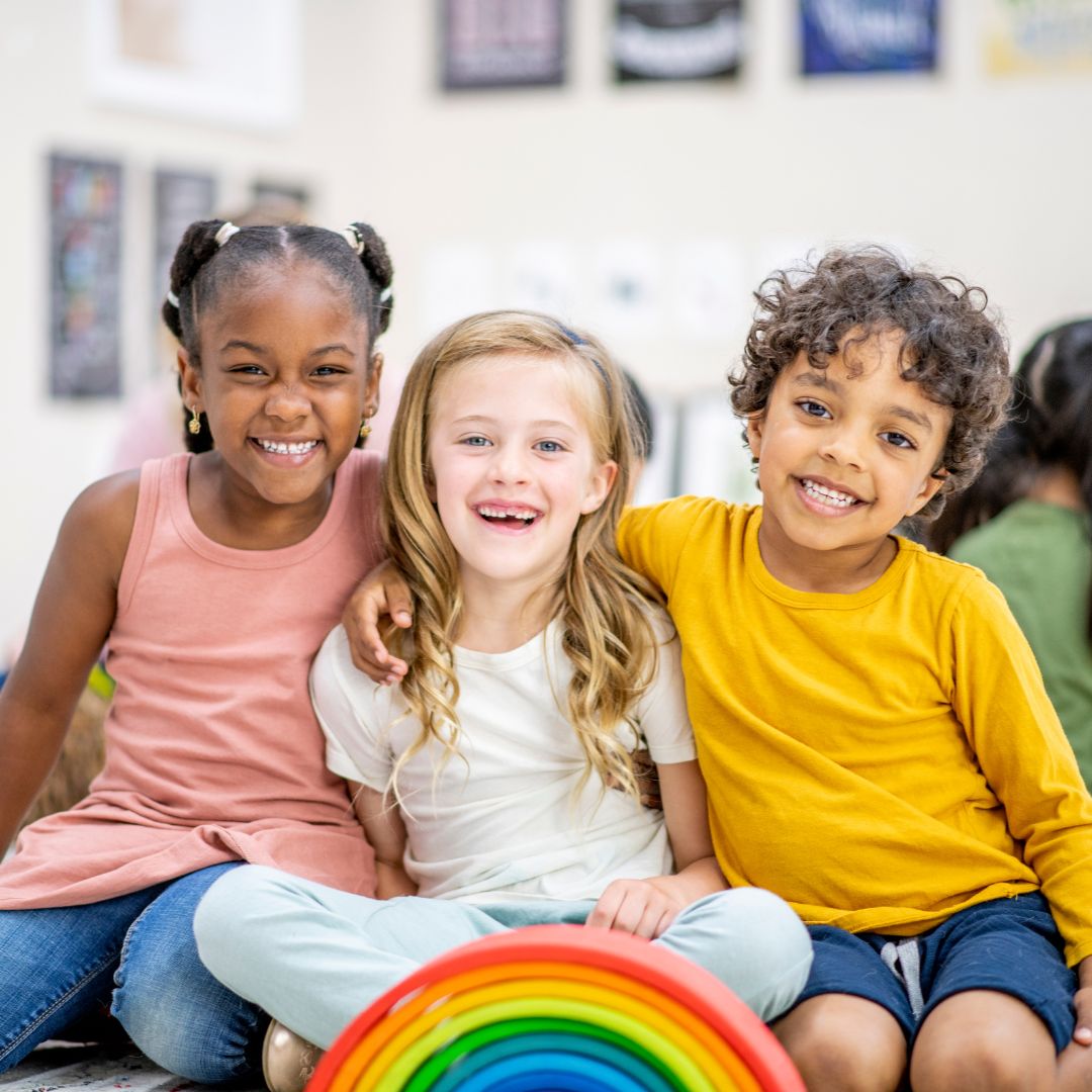 children smiling for camera, rainbow toy