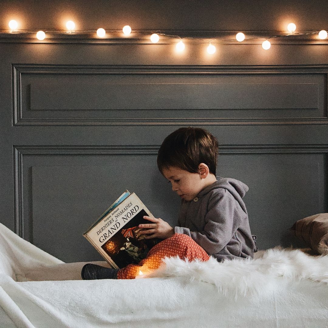 toddler reading in their bed